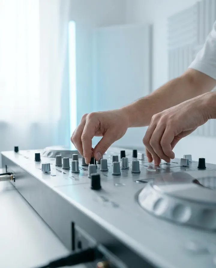 A DJ's hands on a silver mixer, a frame from a release promo video