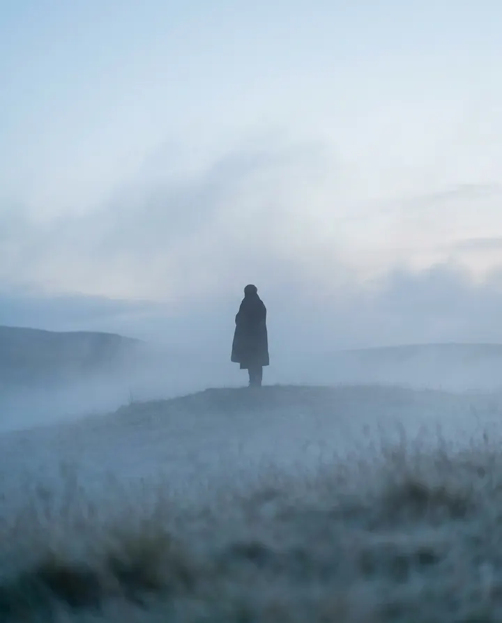 A lone figure on a misty hilltop at dawn, a frame from an indie music visualiser