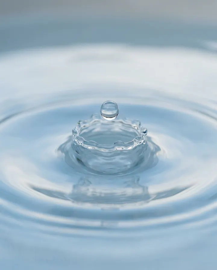 A water drop landing in still blue water, a frame from a faceless explainer Short