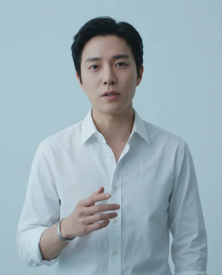 A presenter in a white shirt against a pale blue backdrop, a frame from an ad test