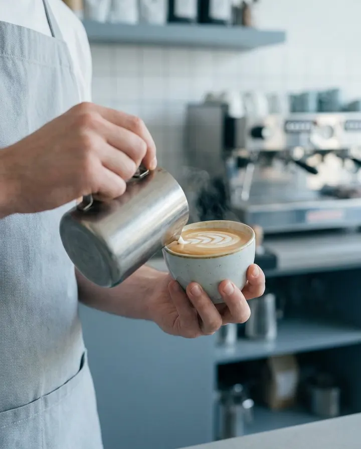 A barista pouring latte art, a frame from a vertical social clip