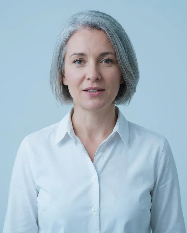 A presenter with short grey hair speaking to camera against a pale blue backdrop, a frame from an explainer